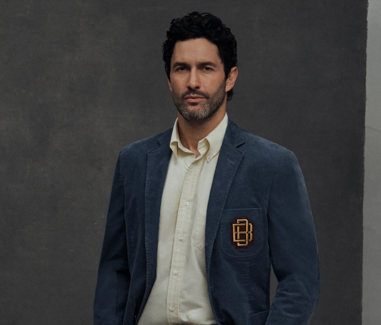 Ein Mann, der einen eleganten blauen Blazer mit dem Brooks Brothers-Logo trägt, gepaart mit einem weißen Freizeithemd, mit einem raffinierten Look