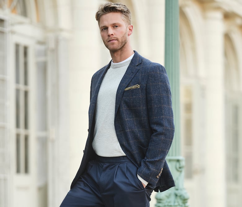 A man in a stylish blue blazer featuring the Brooks Brothers logo, paired with a crisp white casual shirt, exuding a polished look