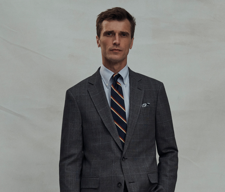 Un hombre con traje gris oscuro, camisa azul y corbata, de pie y con actitud profesional